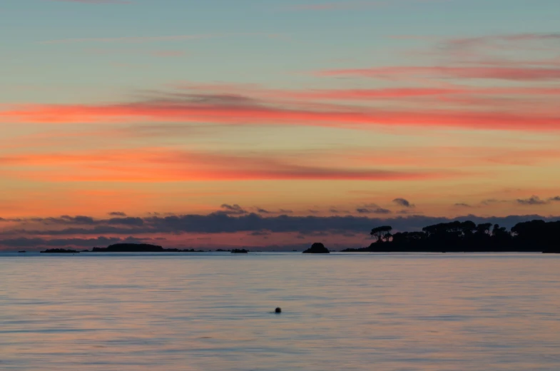 the sun is setting over a small island