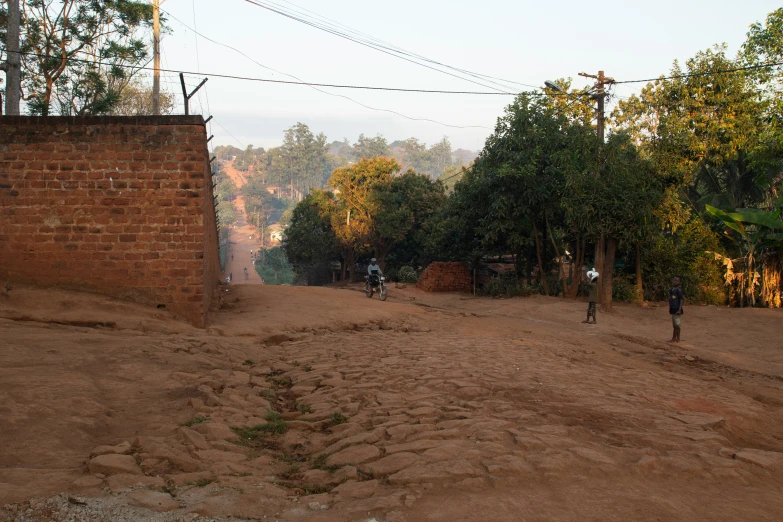 people walking and riding their bikes down a dirt road