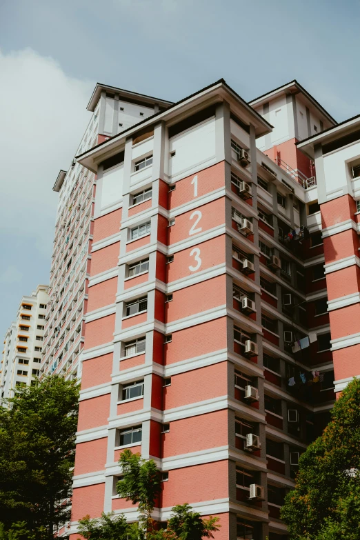 a tall red building next to trees and bushes