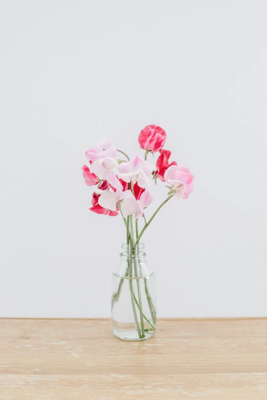 the pink flowers in a vase are on a table