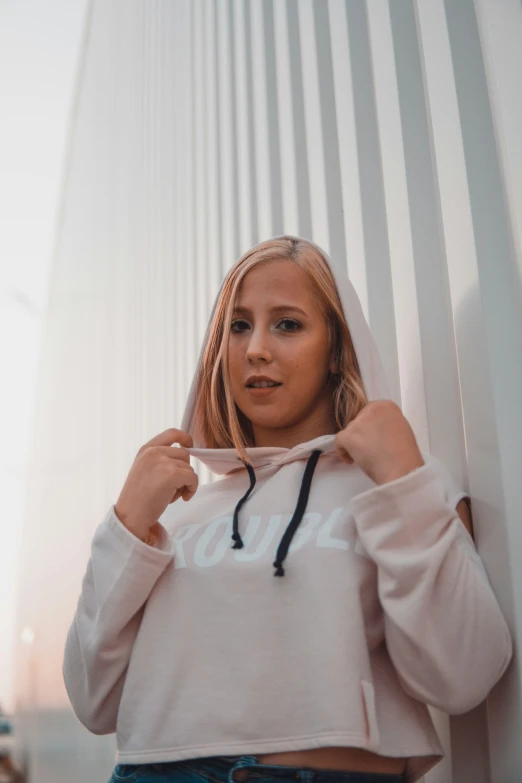 a person wearing a white hoodie near a wall