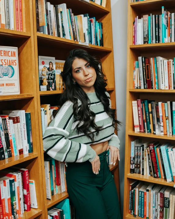 a woman leaning on a book shelf in front of a bookshelf