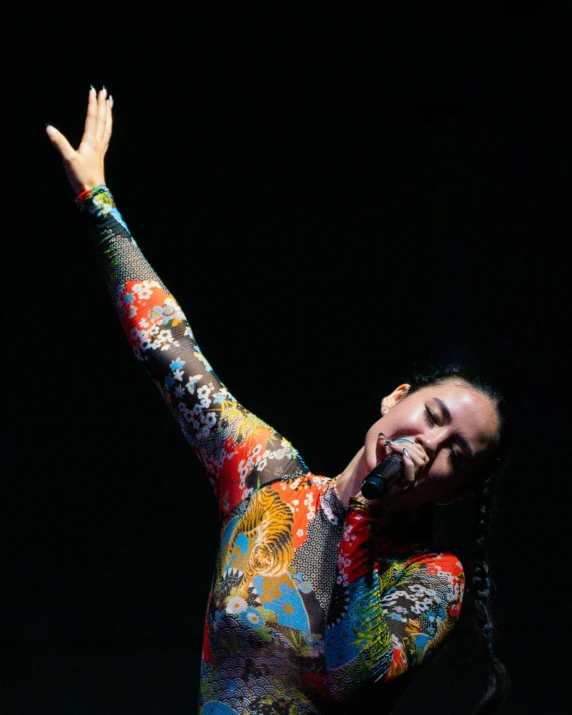 a man in a colorful suit and long sleeved shirt on stage