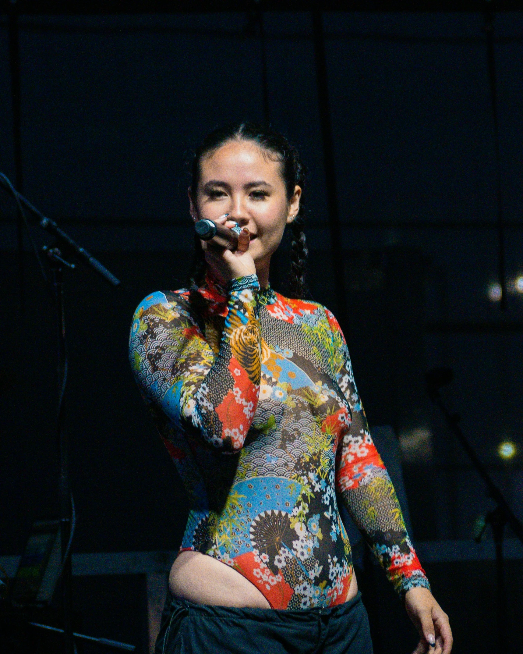 a woman with a microphone is wearing a colorful shirt