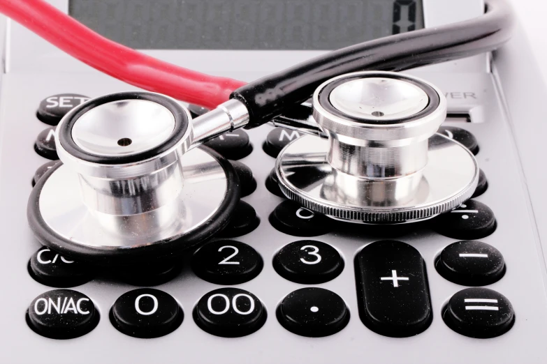 a red stethoscope on top of a calculator