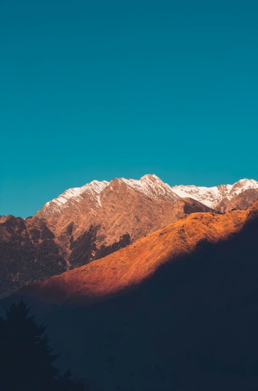 a lone plane flies over a snow - covered mountain range