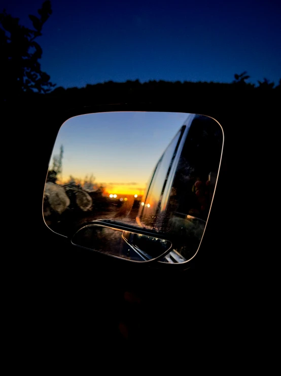 the rear view mirror in the reflection of a person at dusk