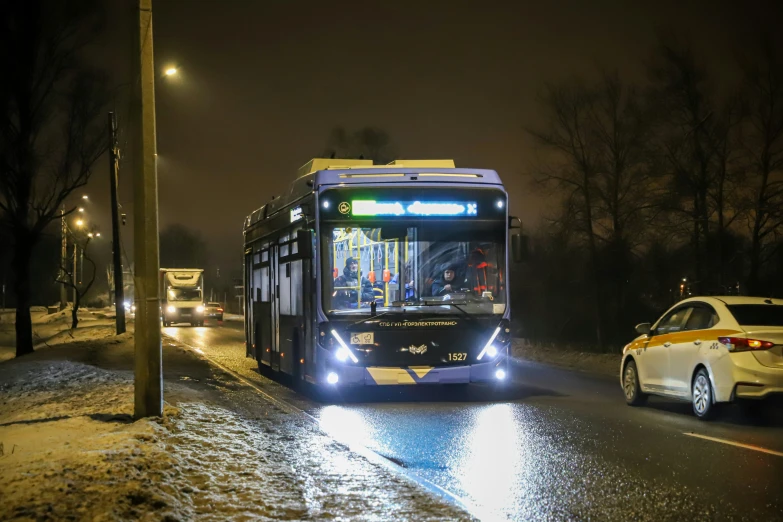 a bus on the road near traffic on a snowy night